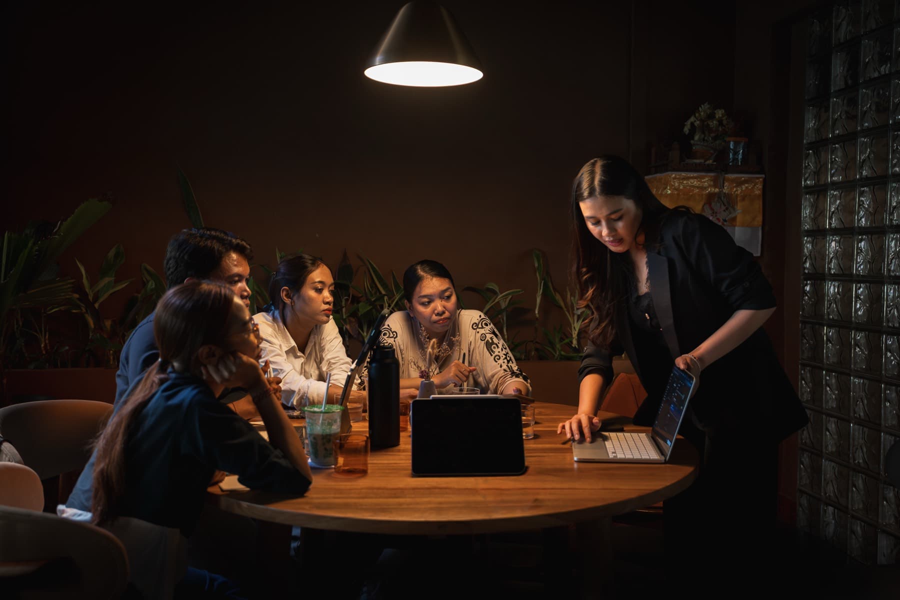 Yulia from Revasi training a venue team around a table under a low pendant light