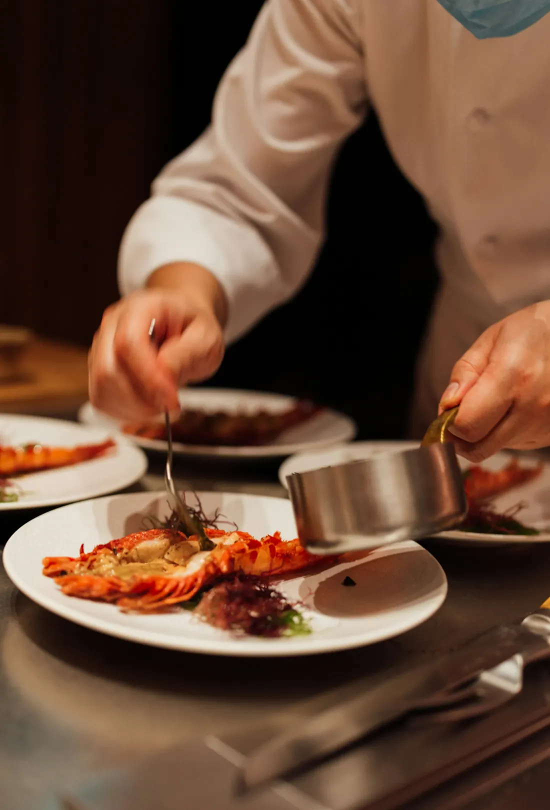 A chef finishing plates of lobster at the pass