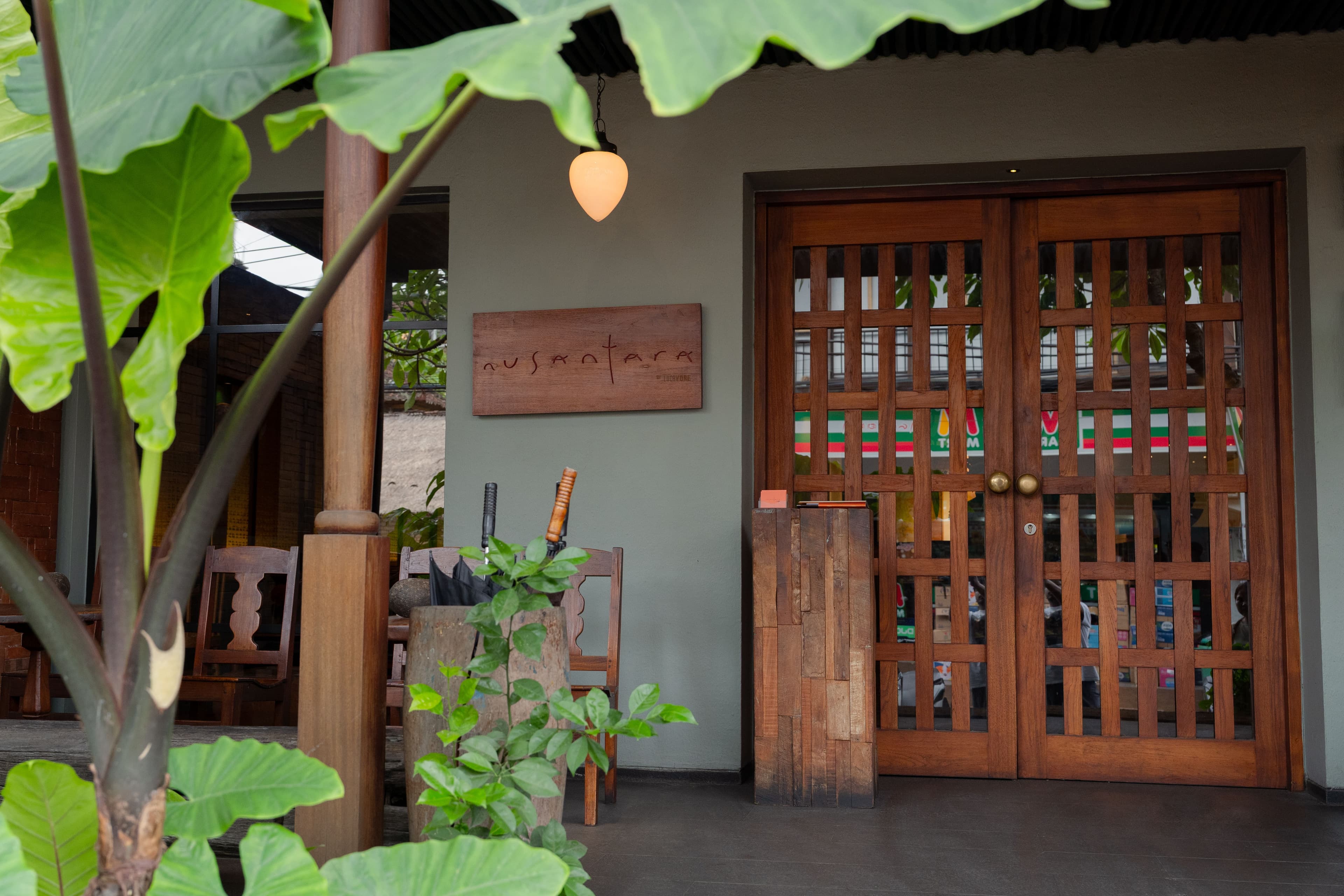 The entrance to Nusantara by Locavore in Ubud, with its carved wooden sign and latticed teak doors.